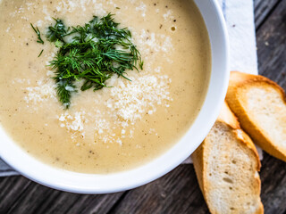 Cream garlic and parmesan soup on wooden table
