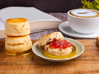 Scones with clotted cream and strawberry jam with tea or coffee on a wooden tray. Side view. Scone traditional English delicious fresh bake homemade