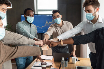 Portrait of diverse business people in masks giving fist bump