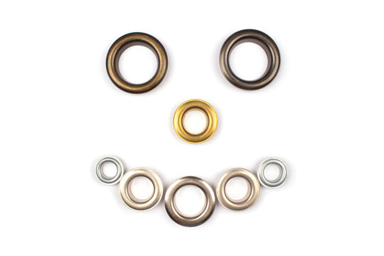 Set of brass multicoloured metal eyelets or rivets - curtains rings for fastening fabric to the cornice, isolated on white background with copyspace for text. Catalogue photo, selective focus