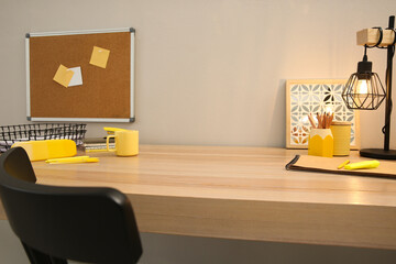 Stylish workplace with stationery on wooden desk near light wall. Interior design