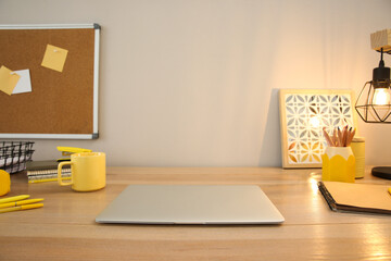 Obraz premium Stylish workplace with laptop on wooden desk near light wall. Interior design