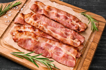 Hot fried bacon with rosemary on a black background.