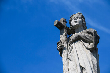 Statue of an angel with a cross on a background of blue sky