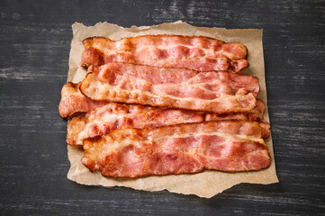 Hot fried bacon on a black background, deliciously
