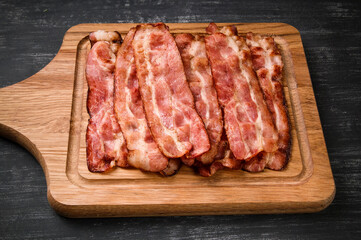 Hot fried bacon on a black background, deliciously