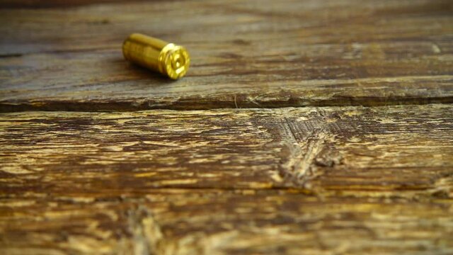 Bullet casings from a 5mm pistol falling closeup on the old vintage wooden floor. Slow motion. 5 mm handgun ammo.