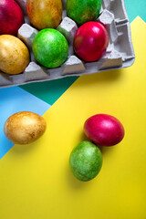 Colored eggs into a nest on a multicolored background .