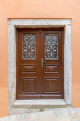 brown frame and panel door, surrounded by weathered concrete, light orange house front