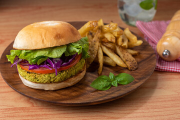 vegan and vegetarian hamburgers and medallions made of legumes and vegetables with potatoes and a glass of fresh water on wooden plate
