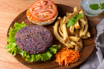 vegan and vegetarian hamburgers and medallions made of legumes and vegetables with potatoes and a glass of fresh water on wooden plate
