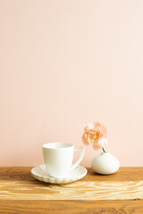White coffee cup with carnation flower on wooden table. pink background