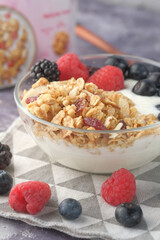 yogurt, granola and berries in bowl on wooden background 