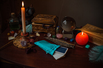 A fortune teller, witch stuff on a table, candles and fortune-telling objects. The concept of...