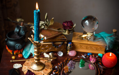 A fortune teller, witch stuff on a table, candles and fortune-telling objects. The concept of divination, astrology and esotericism