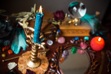 A fortune teller, witch stuff on a table, candles and fortune-telling objects. The concept of divination, astrology and esotericism