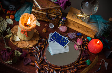 A fortune teller, witch stuff on a table, candles and fortune-telling objects. The concept of...