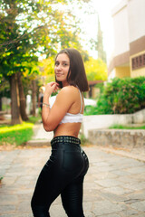Attractive Hispanic female in leather pants posing outdoor