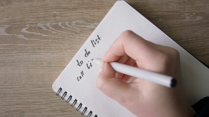 Female hands making list in to do note in notebook. Top shot, close up