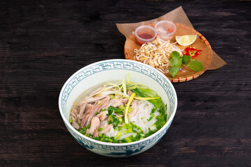 soup with pieces of chicken fillet, rice noodles, greens, green onions and lime, mint