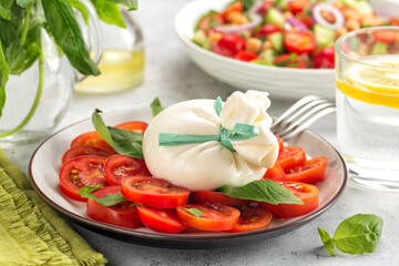 Italian summer dinner. Close-up of  burrata cheese on tomatoes and basil leaves.