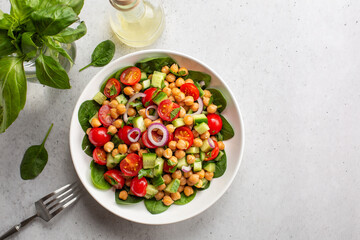 Fresh summer mediterranean salad with chickpea, tomatoes, cucumbers, spinach, red onion, parsley....