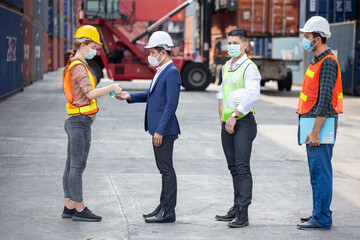 manager wear face mask scanning body temperature and using hand sanitizer alcohol gel to worker before entering working over Containers box at logistic Cargo during Coronavirus or Covid 19 pandemic