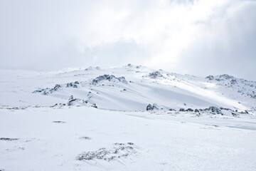 Rocky snowy mountain top, filled with soft white snow on a cloudy day