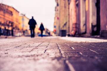 Winter in a big city, a pedestrians walking along a snowy street. Close up view from the sidewalk level