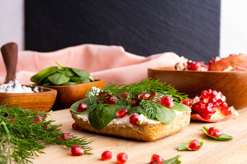 half bun with healthy fresh cream, young spinach leaves, ripe pomegranate grains and green dill