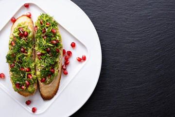 healthy snacks - avocado, sprinkled with ripe pomegranate seeds, sesame seeds and fresh dill