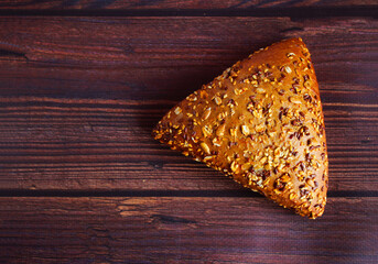 Whole grain loaf on a wooden background. Roll with sesame seeds, flax, seeds. Bread. View from above. Selective focus