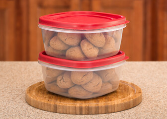 Freshly baked molasses cookies sealed in plastic food containers on kitchen countertop.