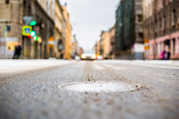 Snowy winter in the big city, the car rides on a green traffic light signal. Close up view of a hatch at the level of the asphalt
