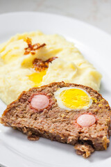 meat loaf filled with egg and sausage served with mashed potatoes and fried onion