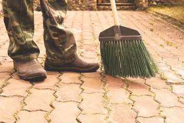 The janitor sweeps in the courtyard, cleans the territory near the house on the street