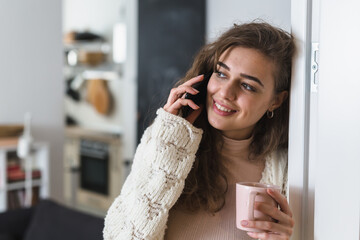 woman drinking morning coffee at home and using mobile phone