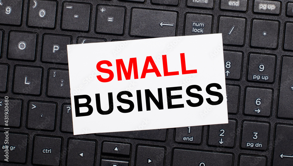 Poster on a black computer keyboard there is a white card with the text small business. view from above