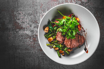 Roast beef salad with green beans and mushroom in a bowl on Dark grey black slate background