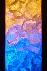Glasstücke liegen übereinander und werden mit blauem und gelbem Licht beleuchtet.