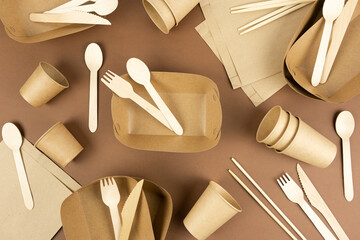 A set of disposable tableware and wood cutlery on brown background. Fast food containers....