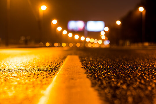 Foggy Night In The Big City, The Empty Street Lighting Lanterns With Billboard On The Road. Close Up View From The Level Of The Dividing Line