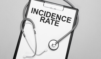The words incidence rate is written on white paper on a grey background near a stethoscope. Medical...