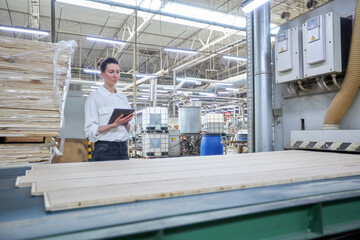 Business woman worker in the carpentry factory using tablet pc. Carpentry factory. Factory for the production of parquet board
