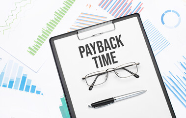 PAYBACK TIME sign. Conceptual background with chart ,papers, pen and glasses