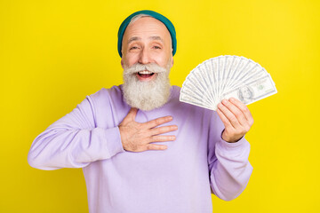 Photo of pretty impressed mature man dressed purple pullover headwear holding money arm chest...