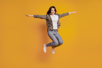 Fototapeta na wymiar Full length photo of woman raise hands jump isolated over yellow background