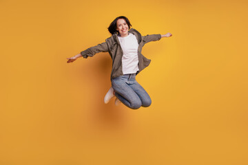 Full length photo of young woman raise fly hands jump isolated over yellow background