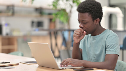 Sick Young African Man with Laptop Coughing