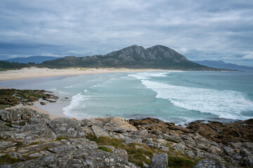 Punta Canton amazing landscape view with mountain, beach and surfers surfing on the atlantic ocean sea, in Spain